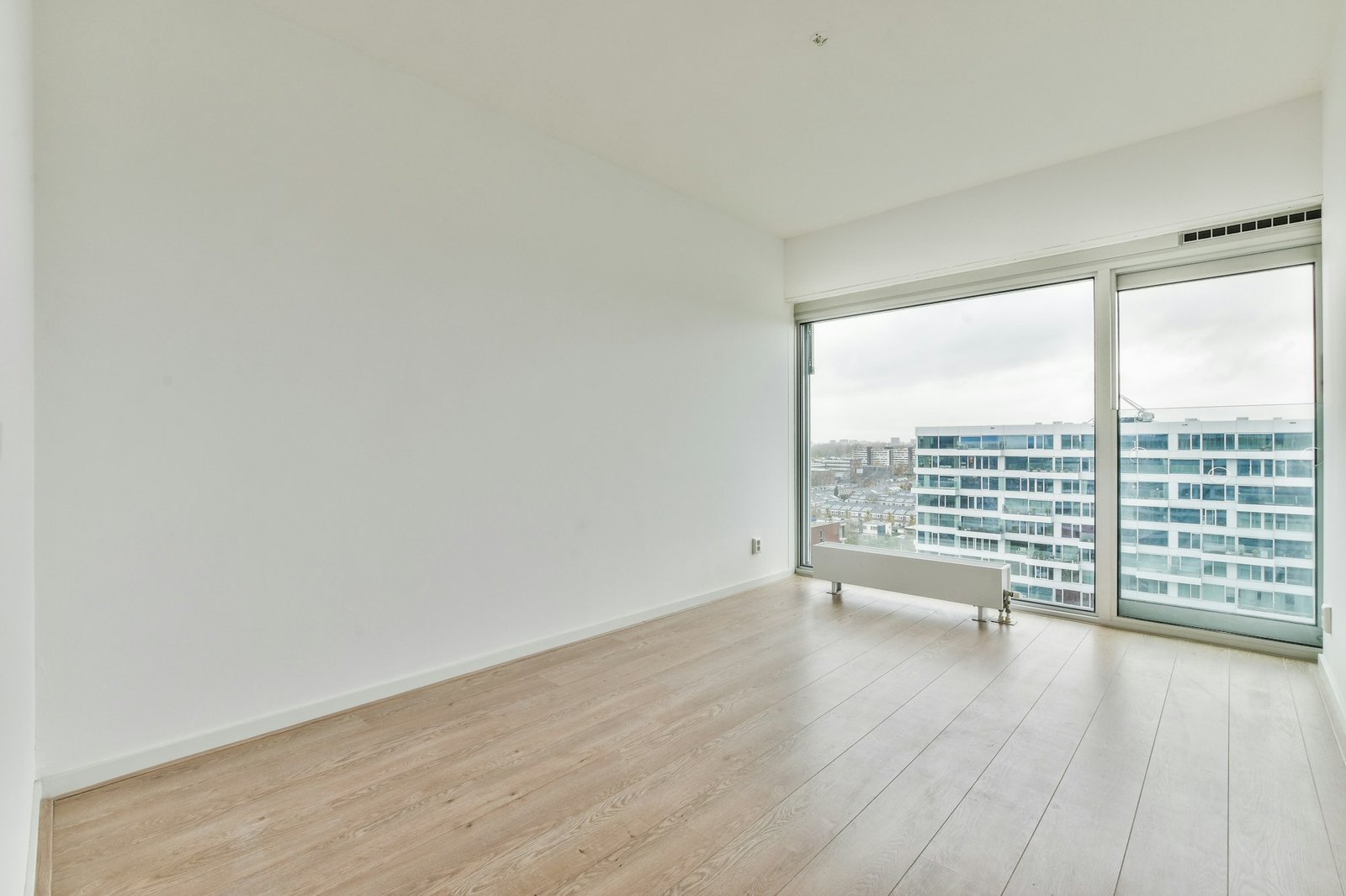 Empty white room with laminate flooring and french windows